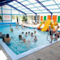 Bambini che giocano in piscina coperta con scivolo al villaggio vacanze ’t Strandheem a Groningen, Paesi Bassi.