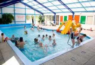 Children playing in an indoor pool with a slide at holiday park ’t Strandheem in Groningen, Netherlands.