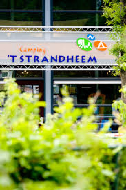 Entrance sign for ’t Strandheem holiday park, surrounded by greenery, located in Groningen, Netherlands.