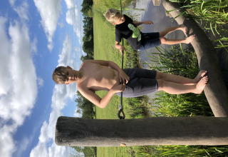 Dos niños equilibrándose sobre troncos de madera en el agua en ’t Strandheem, Groningen, Países Bajos.