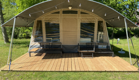 Tente glamping avec terrasse en bois et sièges extérieurs au parc ’t Strandheem, à Groningue, Pays-Bas.