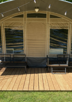 Tenda glamping con terrazza in legno e posti a sedere all'aperto al parco ’t Strandheem, Groningen, Paesi Bassi.