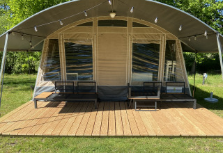Tente glamping avec terrasse en bois et sièges extérieurs au parc ’t Strandheem, à Groningue, Pays-Bas.