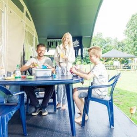 Familie nyder feriestemning ved at sidde sammen udenfor en campingvogn i ferieparken ’t Strandheem, Groningen.