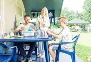 Familie nyder feriestemning ved at sidde sammen udenfor en campingvogn i ferieparken ’t Strandheem, Groningen.