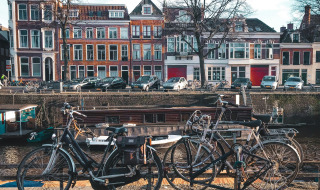 Biciclette parcheggiate lungo un canale con case tradizionali olandesi sullo sfondo a Groningen, Paesi Bassi.