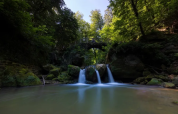 Tranquilla cascata e ponte ad arco nella foresta a Camping Gritt, Diekirch, Lussemburgo.