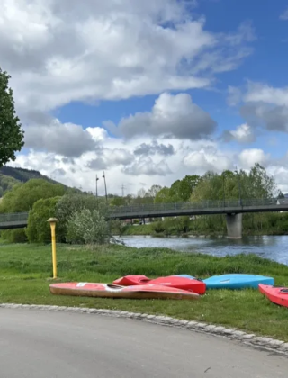 Kayak sull’erba vicino al fiume sotto un cielo nuvoloso presso Camping Gritt, Diekirch, Lussemburgo.