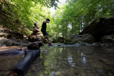 Persona attraversa un ruscello poco profondo a Camping Gritt, immerso nella natura a Diekirch, Lussemburgo.