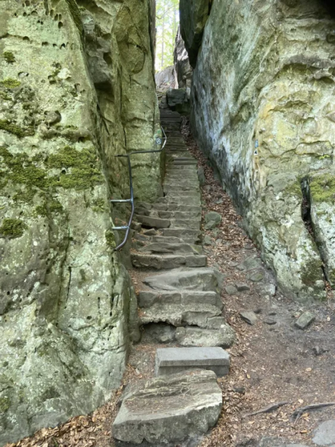 Scalini di pietra tra pareti rocciose coperte di muschio al Camping Gritt, parco vacanze a Diekirch, Lussemburgo.