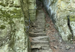 Scalini di pietra tra pareti rocciose coperte di muschio al Camping Gritt, parco vacanze a Diekirch, Lussemburgo.