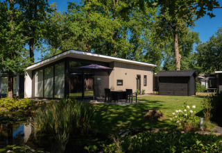Casa vacanze moderna a Bospark Markelo, Overijssel, Paesi Bassi, circondata da alberi e uno stagno.