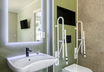 Toegankelijke badkamer met moderne wastafel, hangtoilet en steungrepen bij Veluwehoeve in Bospark Ede.