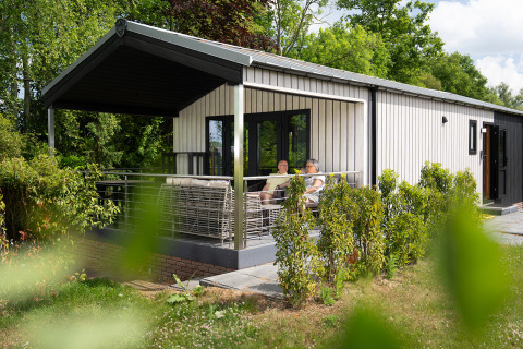 Terraza de una cabaña con sauna y jacuzzi en Holiday Resort 't Schuttenbelt, Países Bajos.