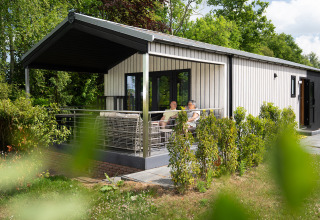 Terraza de una cabaña con sauna y jacuzzi en Holiday Resort 't Schuttenbelt, Países Bajos.