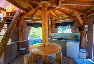 Interno di una tenda tipi unica con cucina rustica e arredi in legno al Camping Des Randonneurs in Francia.