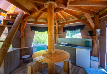 Interno di una tenda tipi unica con cucina rustica e arredi in legno al Camping Des Randonneurs in Francia.