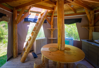 Interior de un tipi burbuja único sin fontanería en Camping Des Randonneurs, con muebles de madera.