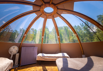 Interior de una tienda tipi burbuja única con camas bajo una cúpula transparente, Camping Des Randonneurs, Francia.