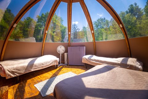 Interno di un originale teepee a bolla senza servizi, con letti e vista sul bosco al Camping Des Randonneurs.
