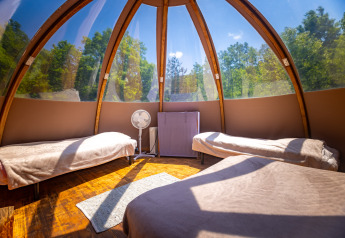 Interno di un originale teepee a bolla senza servizi, con letti e vista sul bosco al Camping Des Randonneurs.