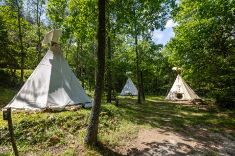 Tiendas tipi sin baños en Camping Des Randonneurs, Francia, rodeadas de árboles y vegetación verde.