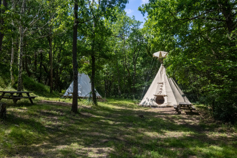 Dos tiendas tipi sin baños en Camping Des Randonneurs en Francia, situadas en un claro del bosque.