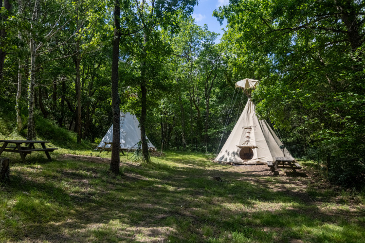 Dos tiendas tipi sin baños en Camping Des Randonneurs en Francia, situadas en un claro del bosque.