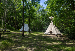 Dos tiendas tipi sin baños en Camping Des Randonneurs en Francia, situadas en un claro del bosque.
