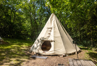 Tienda tipi llamada 'Tipi - sin baños' en Camping Des Randonneurs, rodeada de bosque verde en Francia.