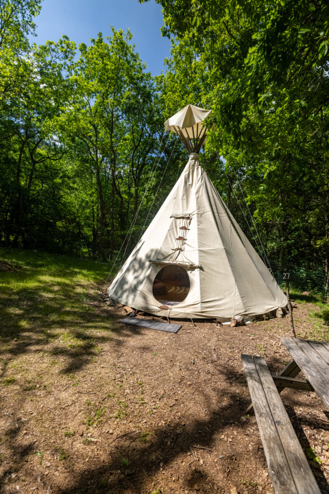 Foto de una tienda tipi sin baños en el Camping Des Randonneurs en Francia, rodeada de bosque.