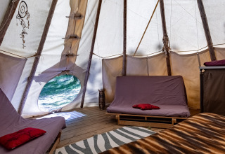 Interior de la tienda Tipi en Camping Des Randonneurs, Francia, con camas, piso de madera y sin baño.