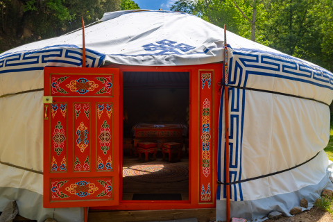 Yurta tradicional con puerta decorada, experiencia de glamping en Camping des Randonneurs, Occitania.