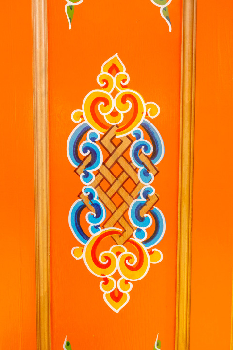 Traditioneel Mongools patroon op een oranje yurtmuur, met verfijnde blauwe en gele details.
