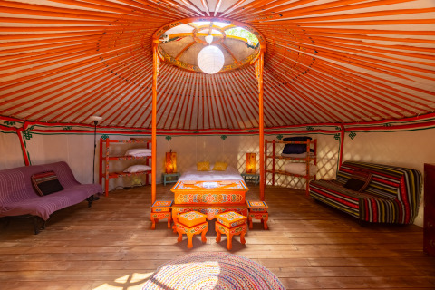 Bunte, traditionelle Jurte mit Holzboden und gemütlicher Inneneinrichtung bei Camping des Randonneurs.