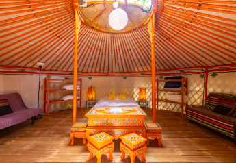 Binnenkant van een authentieke, kleurrijke joert op Camping des Randonneurs - Yurts Occitanië met houten vloer.
