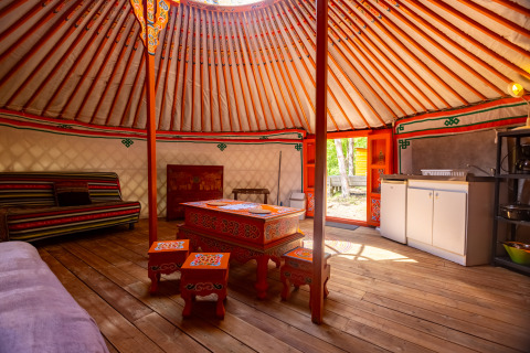 Indretning af en traditionel mongolsk yurt med farverigt træmøblement og moderne bekvemmeligheder.