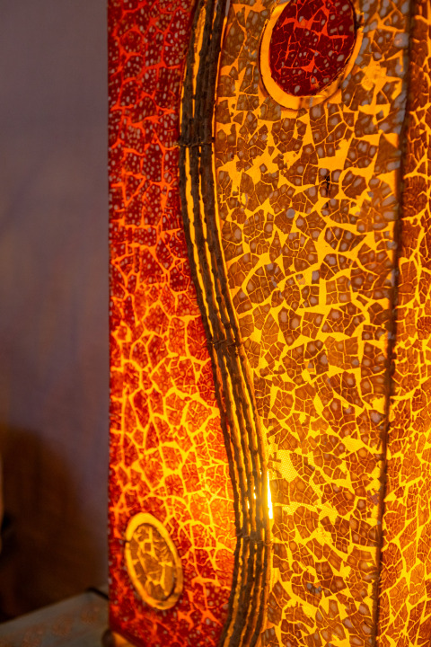 Close-up of a colorful mosaic lamp inside a traditional yurt with warm yellow and red hues.