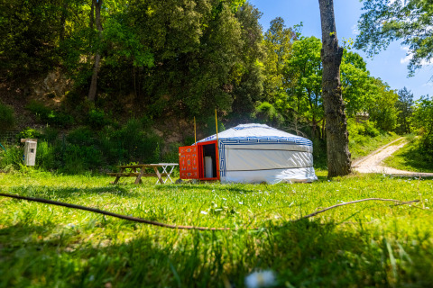 Une yourte traditionnelle au Camping des Randonneurs, installée sur une pelouse entourée d’arbres et de nature.