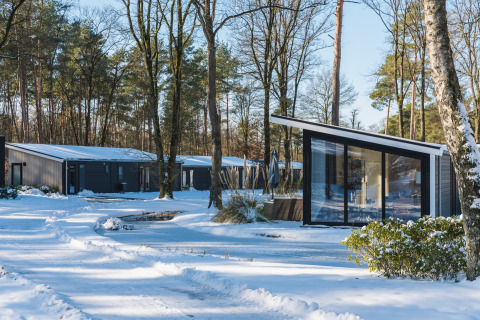Moderne Ferienhäuser im Bospark Markelo, Overijssel, Niederlande, im verschneiten Winterwald gelegen.