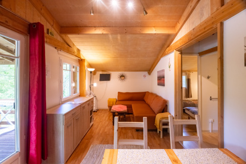 Bright interior view of Chalet at Camping Des Randonneurs in France, featuring wooden accents and cozy seating.