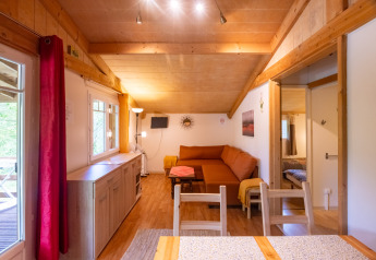 Bright interior view of Chalet at Camping Des Randonneurs in France, featuring wooden accents and cozy seating.