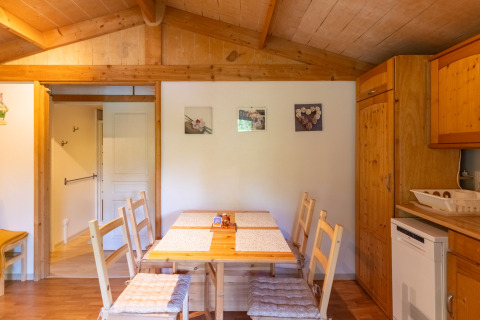 Interior view of dining area and kitchen at Chalet at Camping Des Randonneurs, featuring wood paneling.
