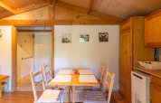 Vista interna della zona pranzo e cucina dello Chalet al Camping Des Randonneurs, con pannelli in legno.