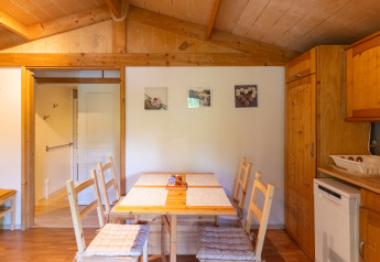Vista interna della zona pranzo e cucina dello Chalet al Camping Des Randonneurs, con pannelli in legno.