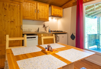 Interior view of the kitchen and dining table in the Chalet at Camping Des Randonneurs, France, with wood décor.