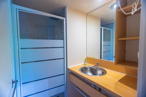 Modern bathroom in a chalet at Camping Des Randonneurs, France, with shower, sink, and large mirror.