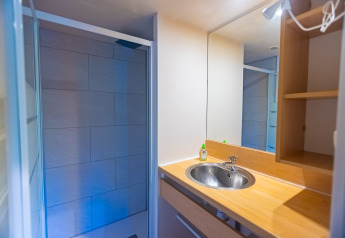 Modern bathroom with sink, mirror, and shower in a chalet at Camping Des Randonneurs in France.