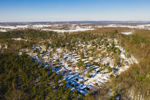 Luftaufnahme des verschneiten Bospark Markelo in Overijssel, Niederlande, umgeben von dichten Wäldern.