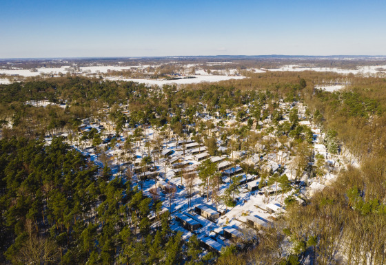 Luchtfoto van het besneeuwde vakantiepark Bospark Markelo omringd door bos in Overijssel, Nederland.